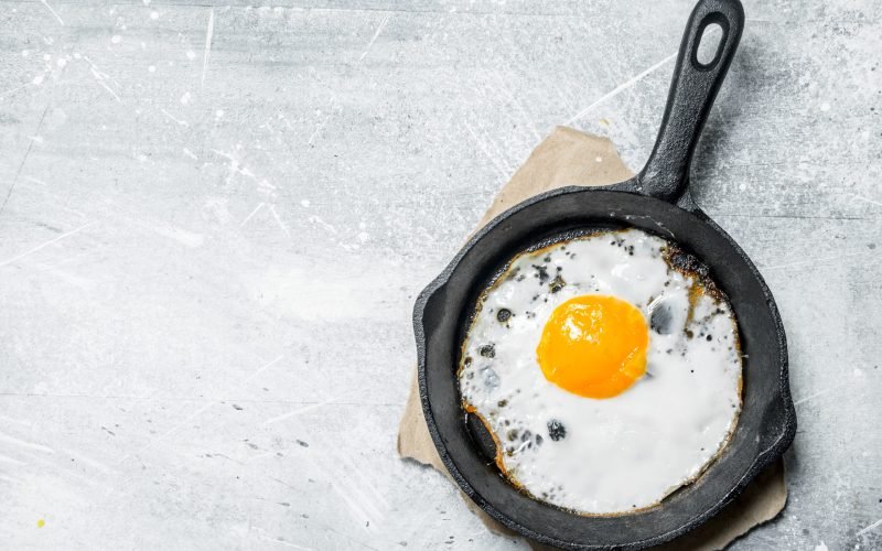 Fried egg in a frying pan. On a rustic background.