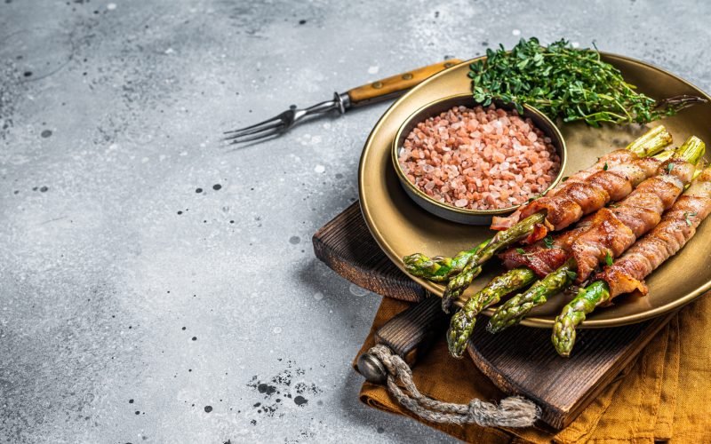 Grilled bacon wrapped  asparagus. Gray background. Top view. Copy space.