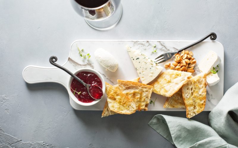 Small cheeseboard with brie, blue cheese, baguette and jam